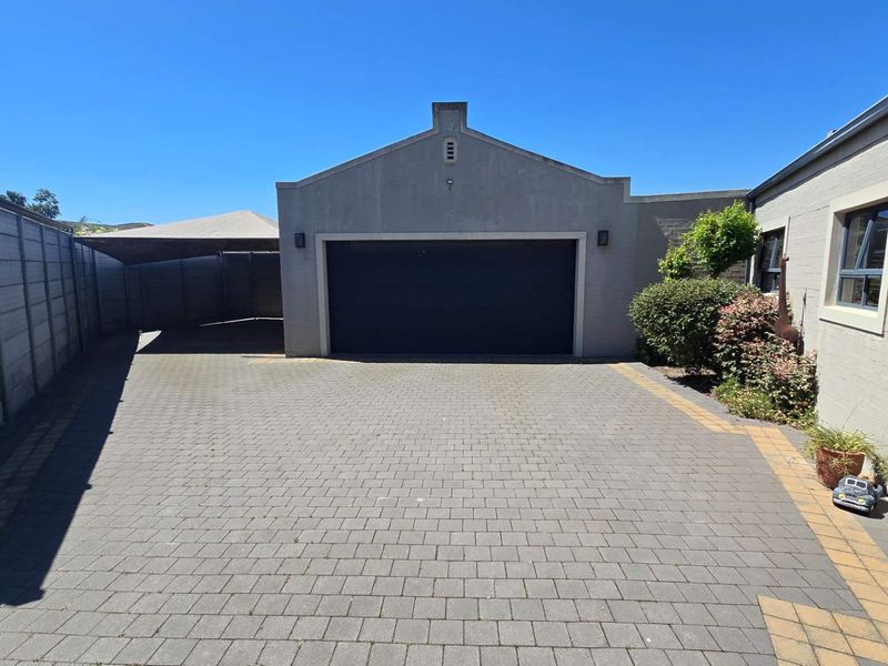 A paved driveway leading to a single garage with a shade sail structure and perimeter boundary walling.