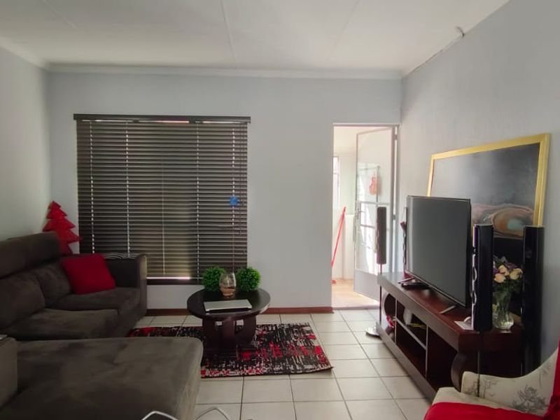 A comfortable living room featuring tiled flooring, coved ceilings, and venetian blinds, providing a functional and well-lit space for relaxation.