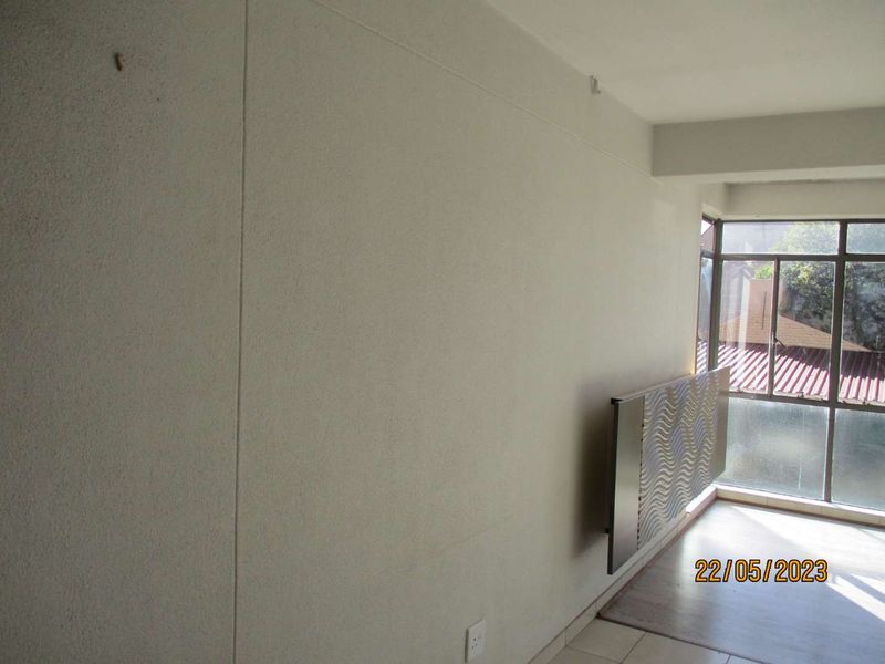 An empty living area featuring a large window and neutral wall finishes, providing a blank canvas for interior design.