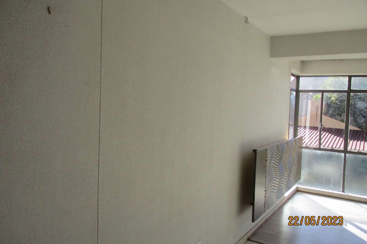 An empty living area featuring a large window and neutral wall finishes, providing a blank canvas for interior design.
