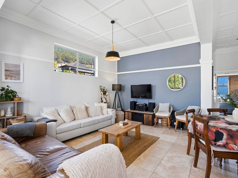 Spacious open-plan living and dining area featuring a distinctive coffered ceiling, tiled flooring, and a feature wall, offering a bright and comfortable living space.