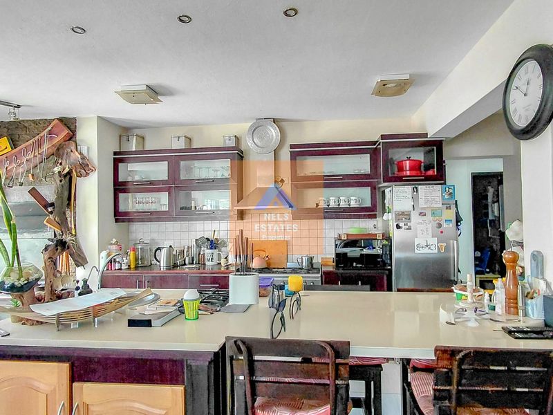 A functional kitchen featuring dark wood cabinetry, a large central island with stone countertops, and a tiled backsplash, offering ample workspace and storage.