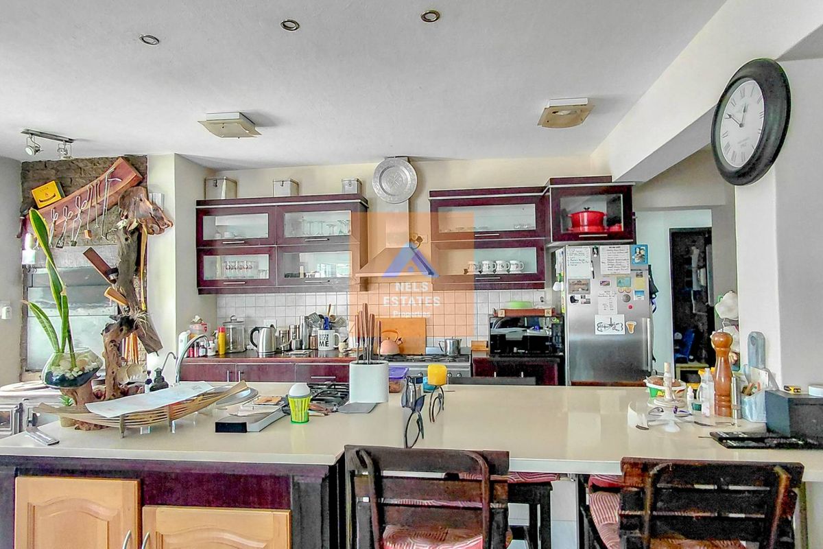 A functional kitchen featuring dark wood cabinetry, a large central island with stone countertops, and a tiled backsplash, offering ample workspace and storage.