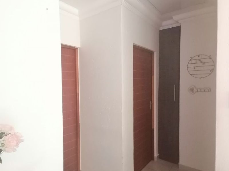 A clean and functional hallway featuring tiled flooring, built-in storage cabinetry, and neutral wall finishes.