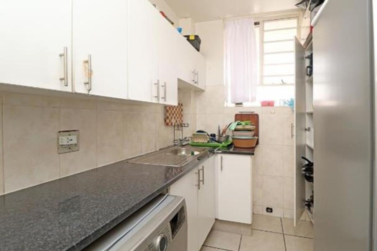 Compact kitchen featuring granite countertops, white built-in cabinetry, tiled backsplash, and tiled flooring with a functional layout.
