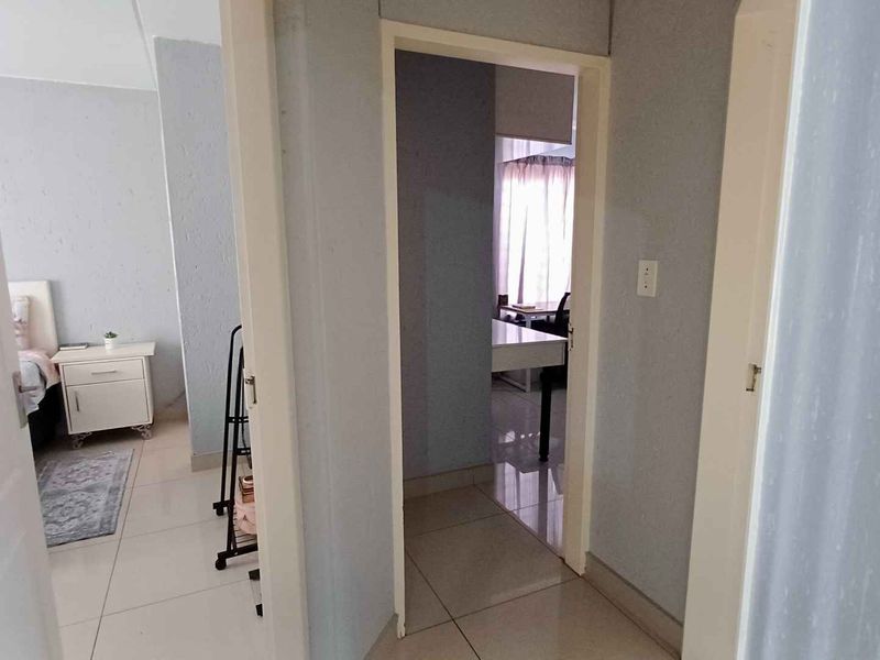 A central hallway with tiled flooring providing access to adjacent rooms within the apartment.