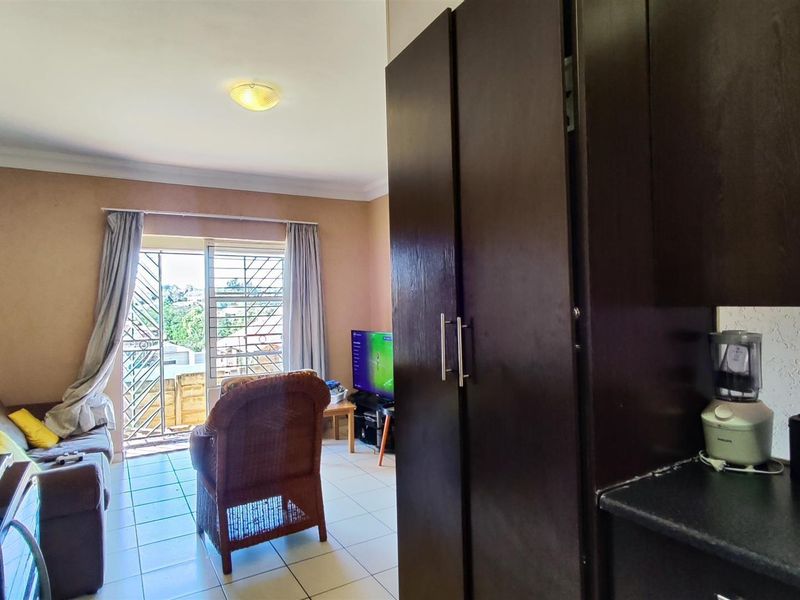 Open plan living area featuring tiled flooring, built-in cabinetry, and a sliding door leading to an outdoor space with security gate.