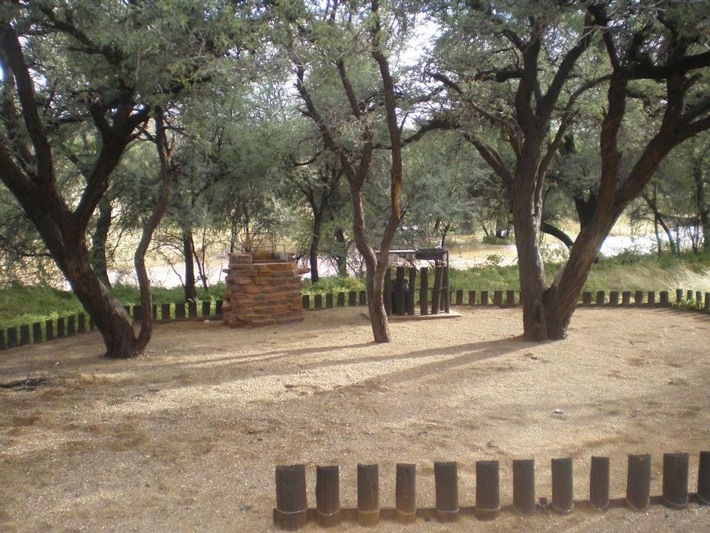 Campsite with fireplace and basin next to a riverbed