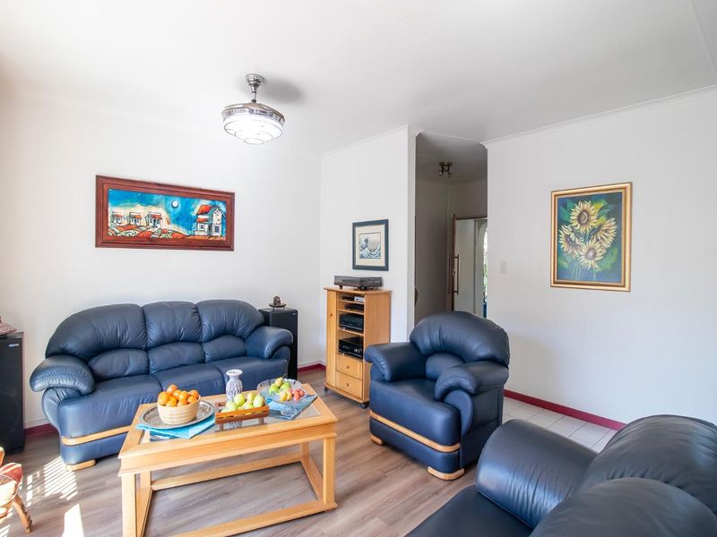 A bright living room featuring laminate flooring, neutral walls, and a central ceiling fan, providing a comfortable and functional space for relaxation.