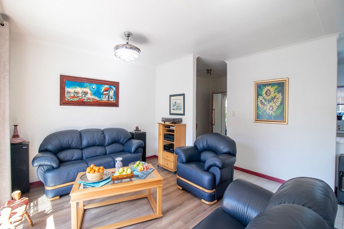 A bright living room featuring laminate flooring, neutral walls, and a central ceiling fan, providing a comfortable and functional space for relaxation.