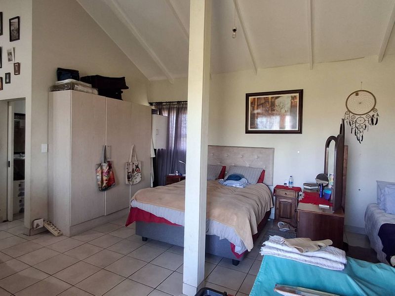 Spacious bedroom featuring a vaulted ceiling, tiled flooring, and a built-in wardrobe, offering a functional layout with ample natural light.