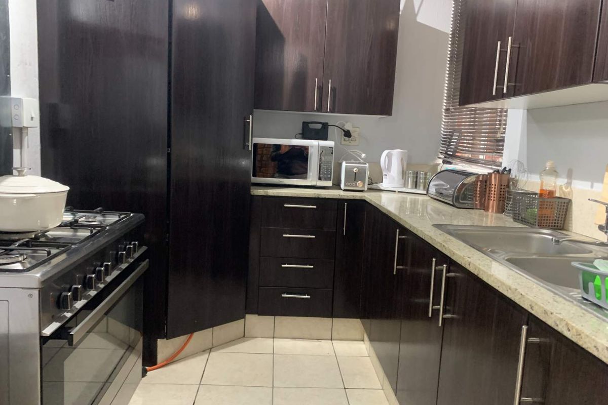 A functional kitchen featuring dark wood cabinetry, granite countertops, a stainless steel gas stove, and a double basin sink.