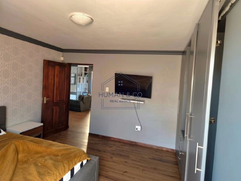 A well-maintained bedroom featuring laminate flooring, built-in cupboards, and a solid timber door, offering a clean and functional living space.