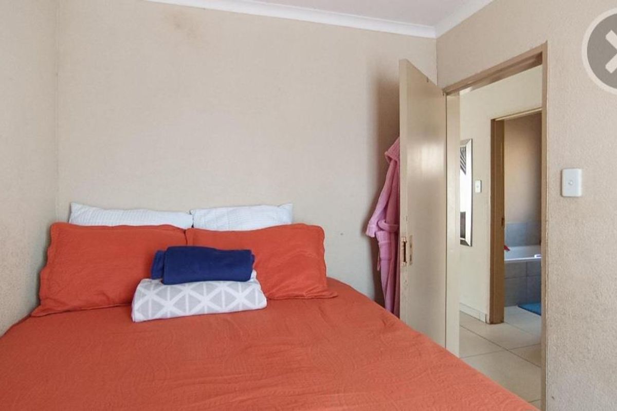 A compact bedroom featuring neutral wall tones and direct access to an adjoining bathroom.