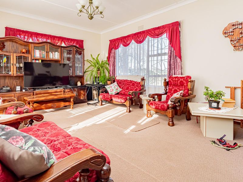 A spacious living room featuring neutral walls, carpeted flooring, and large windows that provide ample natural light.
