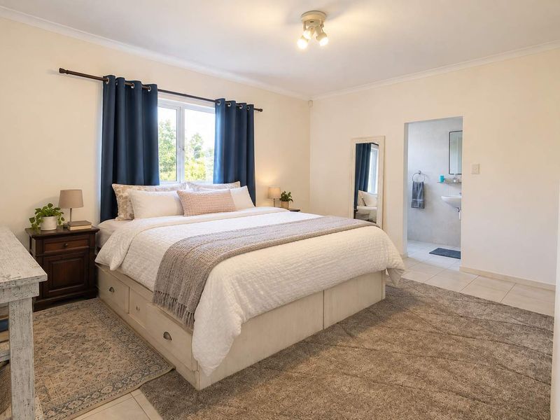 Spacious bedroom featuring neutral walls, tiled flooring, and an attached en-suite bathroom with functional fixtures.