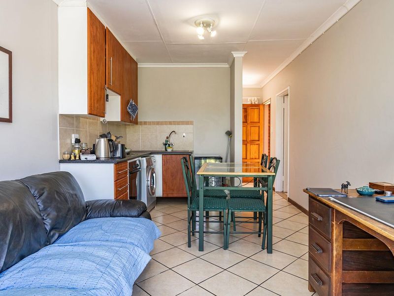 Open-plan living and kitchen area featuring tiled flooring and functional built-in cabinetry, providing a versatile space for dining and relaxation.