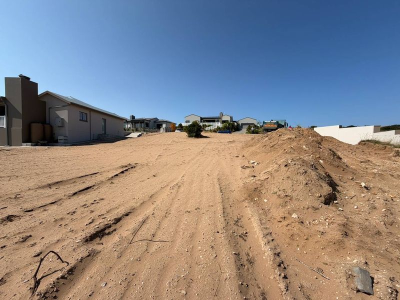 A vacant residential plot of land featuring uneven terrain and exposed soil, situated in a developed neighborhood setting.