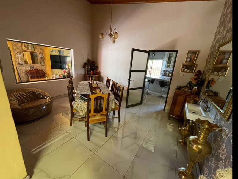 Dining room featuring large format floor tiles, a central light fixture, and an internal door leading to the kitchen area.