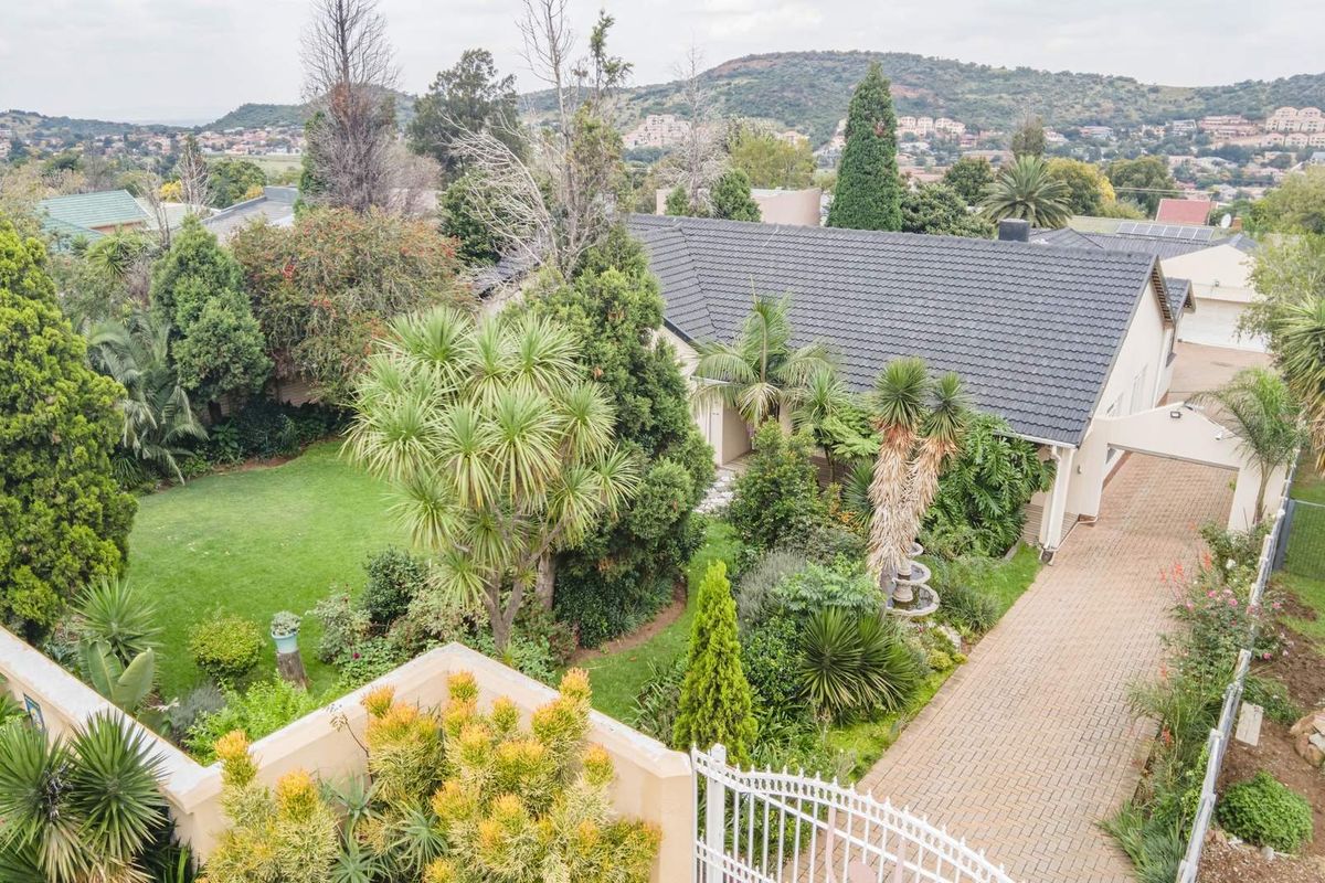 Aerial view of the property showcasing a well-maintained garden, paved driveway, and tiled roof structure within a residential estate setting.