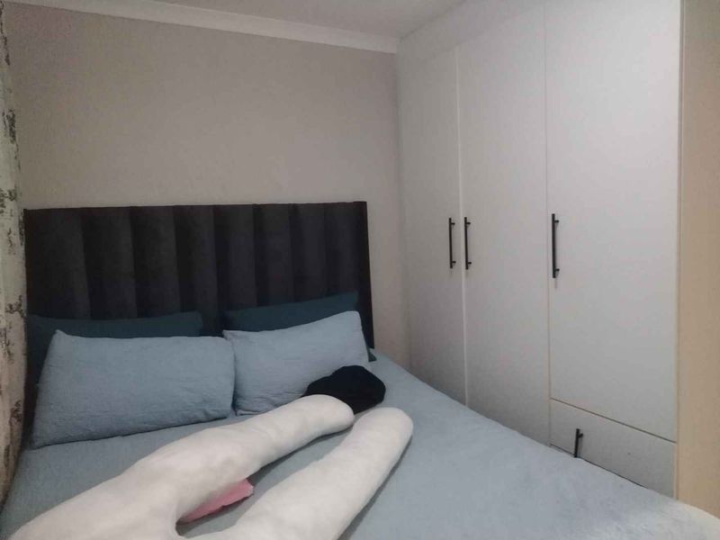 A bedroom featuring a built-in wardrobe with modern handles and neutral wall finishes.