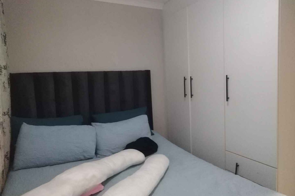 A bedroom featuring a built-in wardrobe with modern handles and neutral wall finishes.