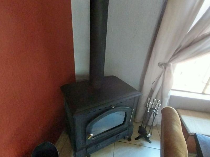 A living area featuring a built-in cast iron fireplace with a vertical flue pipe and tiled flooring.