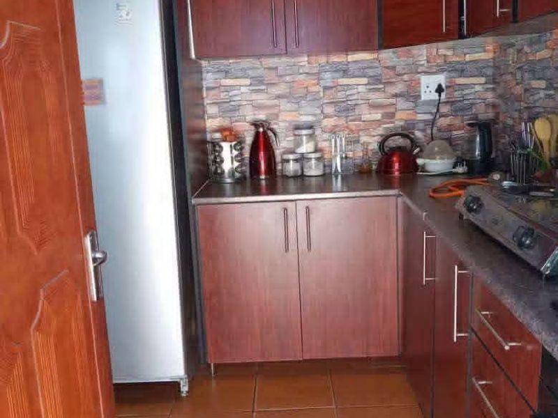 Compact kitchen featuring dark wood-look cabinetry, stone-effect tile backsplash, and ceramic floor tiles, providing a functional and efficient workspace.