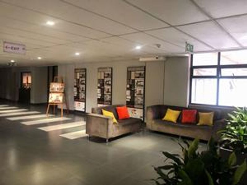 A communal lounge or clubhouse area featuring tiled flooring, recessed lighting, and large windows providing natural light.