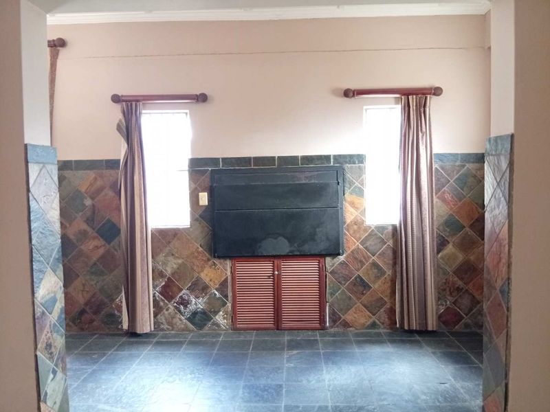 An empty living area featuring a built-in fireplace, slate tile wall cladding, and dark slate floor tiles.