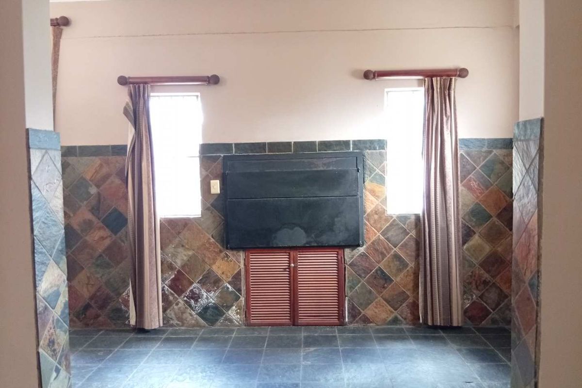 An empty living area featuring a built-in fireplace, slate tile wall cladding, and dark slate floor tiles.