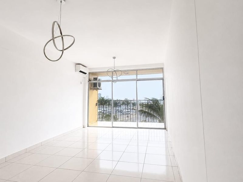 A bright, empty living area featuring tiled floors, modern pendant lighting, a split-system air conditioner, and large sliding glass doors leading to a balcony.