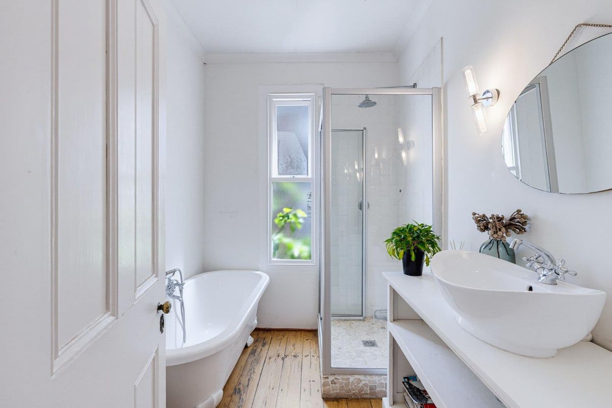 A bright bathroom featuring a classic freestanding bathtub, a separate glass-enclosed shower, and a modern vessel sink set on a custom vanity.