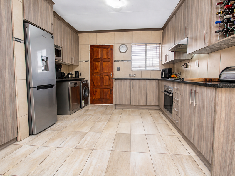 A well-maintained kitchen featuring wood-grain cabinetry, granite-look countertops, tiled backsplash, and integrated appliances, offering a functional and organized culinary workspace.