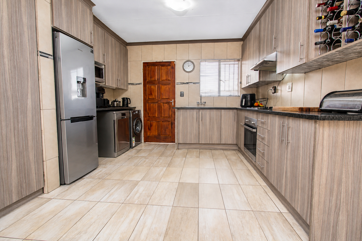 A well-maintained kitchen featuring wood-grain cabinetry, granite-look countertops, tiled backsplash, and integrated appliances, offering a functional and organized culinary workspace.