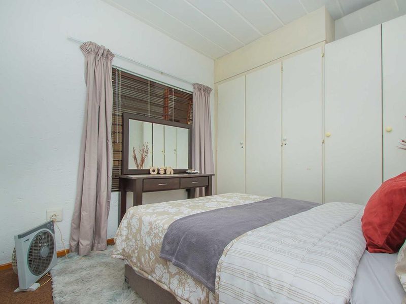 A bedroom featuring built-in cupboards, venetian blinds, and neutral wall finishes, offering a functional space with potential for modern updates.