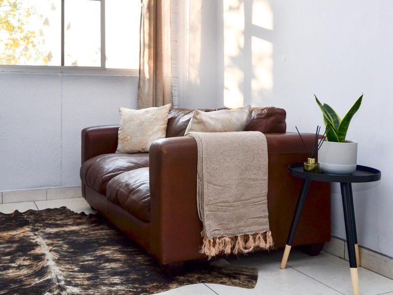 A bright living area featuring neutral tiled flooring and a large window allowing for ample natural light.