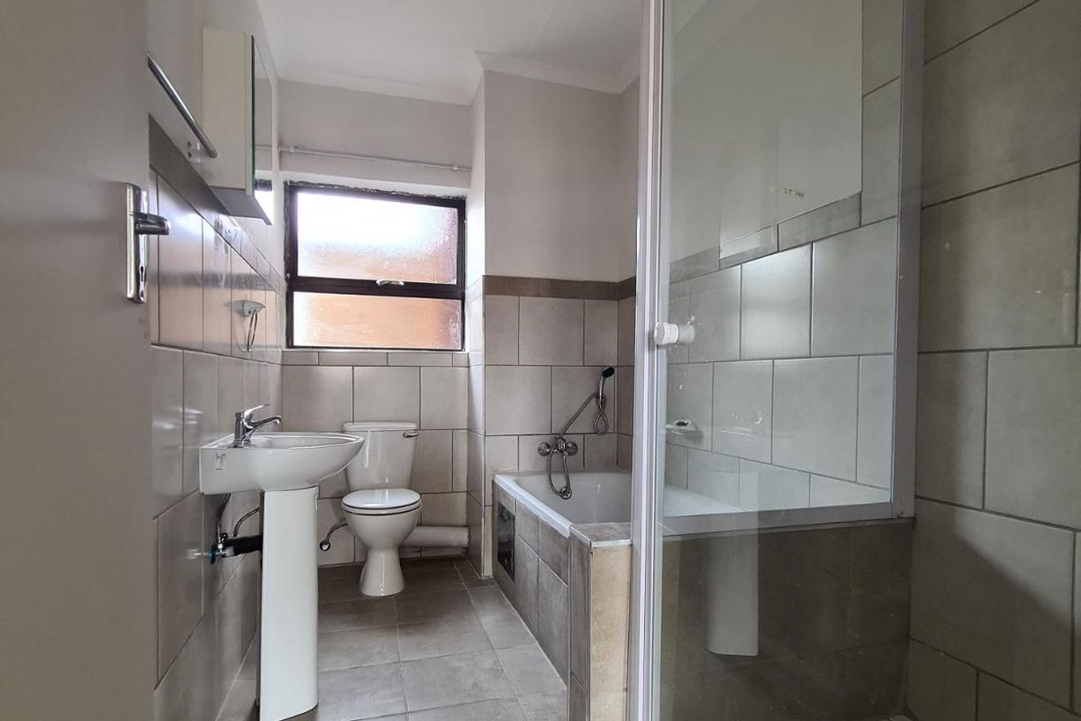 A functional bathroom featuring a pedestal basin, toilet, bathtub, and a separate shower enclosure with tiled finishes throughout.