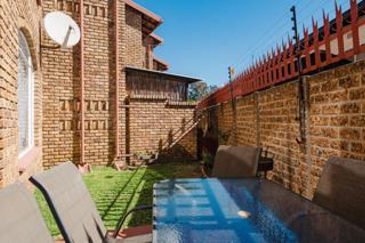 A private rear courtyard area featuring face brick walls and secure electric fencing, providing a low-maintenance outdoor space.