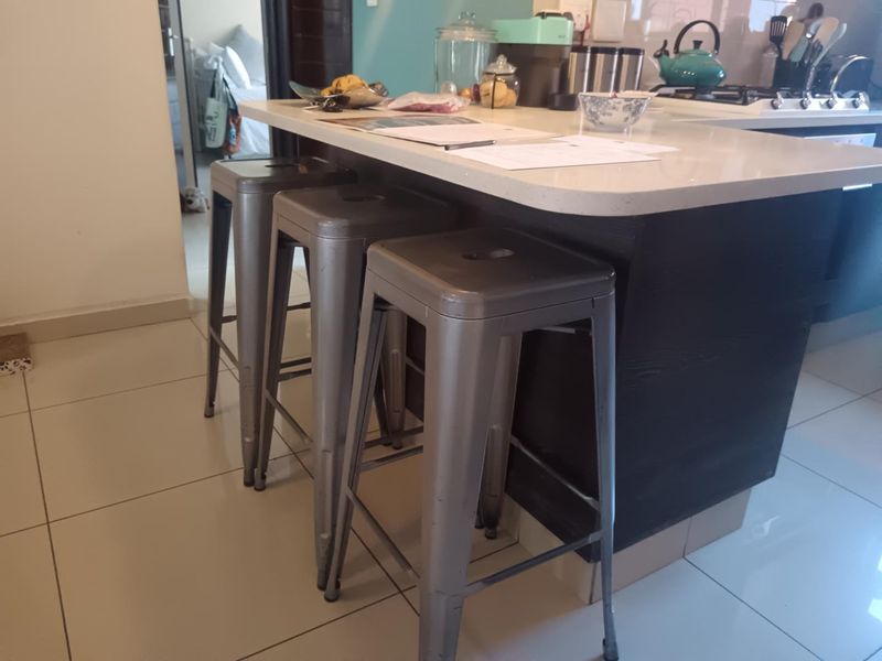 A modern kitchen featuring a central island with a stone countertop, built-in hob, and tiled flooring, providing a functional and contemporary cooking space.