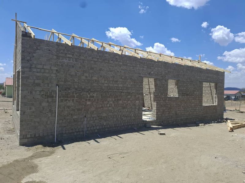 A residential property under construction showing exposed brick walls and timber roof trusses, awaiting further development and finishing.