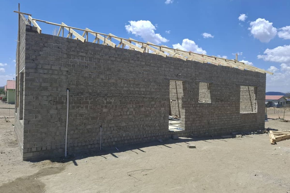 A residential property under construction showing exposed brick walls and timber roof trusses, awaiting further development and finishing.