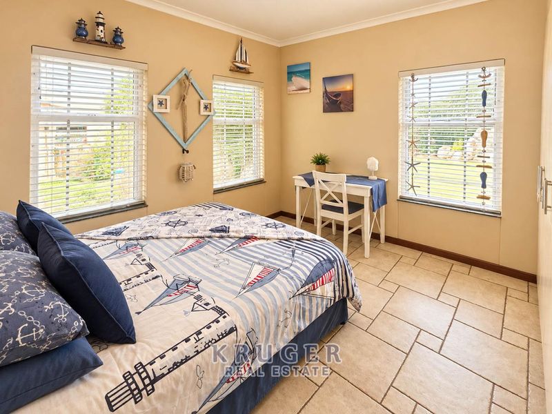A bright bedroom featuring tiled flooring, built-in wardrobe storage, and multiple windows fitted with venetian blinds, offering a clean and functional living space.