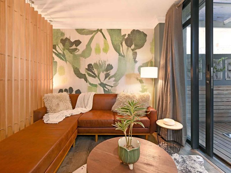 A cozy living area featuring a decorative timber slat partition, modern laminate flooring, and a large sliding glass door leading to an outdoor space.