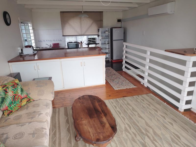 Open-plan living and kitchen area featuring timber flooring, wooden countertops, and a split-system air conditioner, offering a functional layout for daily living.