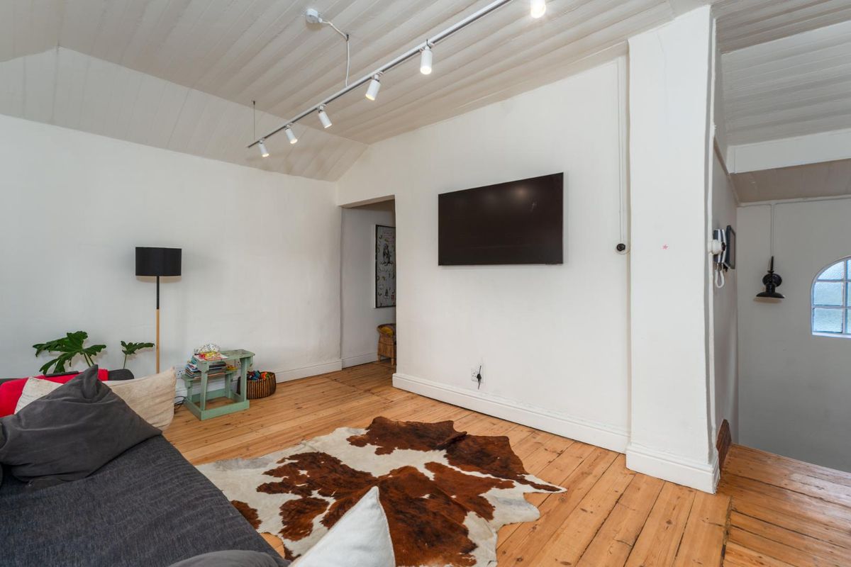 A living room featuring timber flooring, a vaulted timber ceiling, and track lighting, creating a cozy and character-filled space.