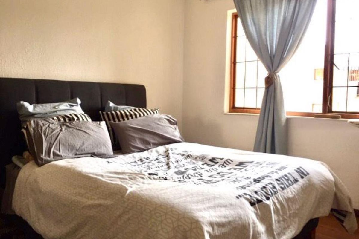 A cozy bedroom featuring a window with a curtain rail, providing natural light and a comfortable living space.