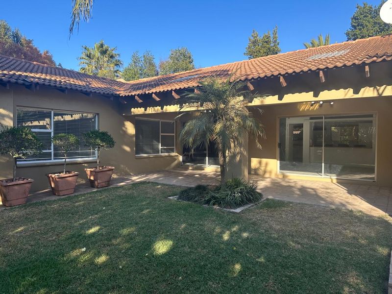 Rear view of the property featuring a covered paved patio, tiled roof with exposed rafters, and sliding glass doors leading into the home.