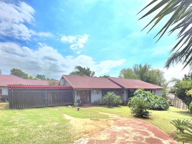 Front view of a residential property featuring a tiled roof, wooden fencing, and a paved driveway set within a landscaped garden.