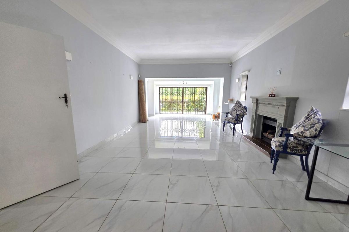 Spacious living room featuring polished marble-look floor tiles, crown molding, and a built-in fireplace, leading to a secure sliding door entrance.